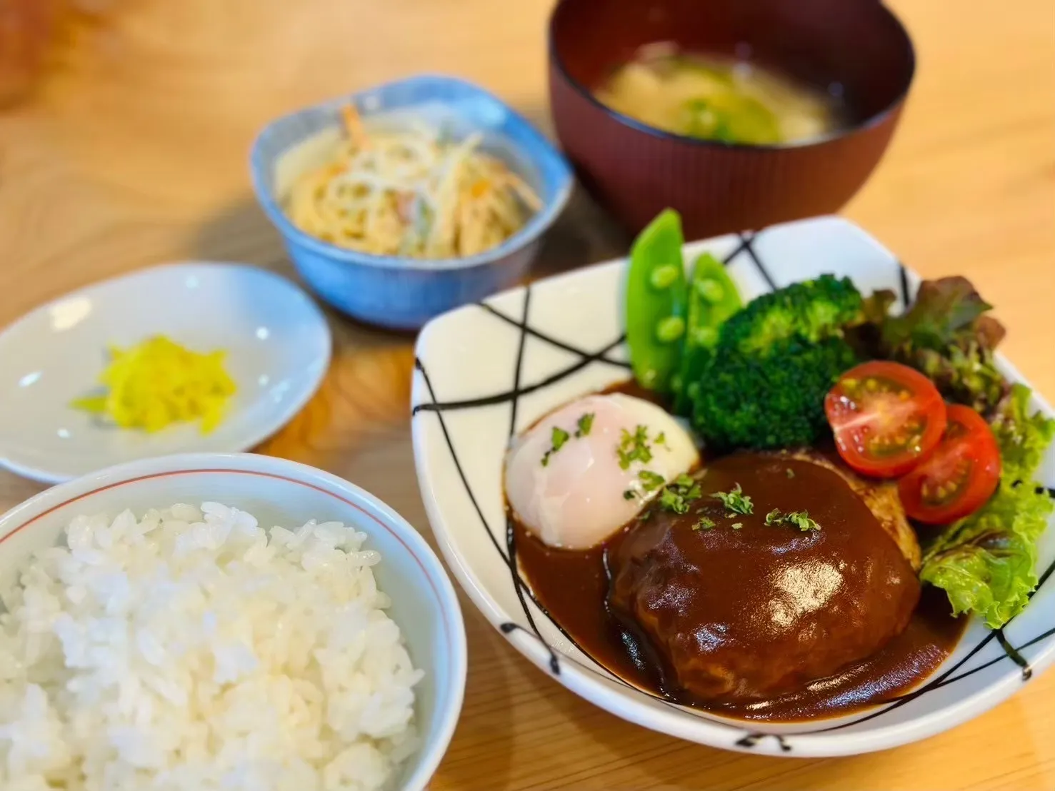 ハンバーグと温泉卵、野菜、ごはん、副菜、汁物が並ぶWILLの昼食